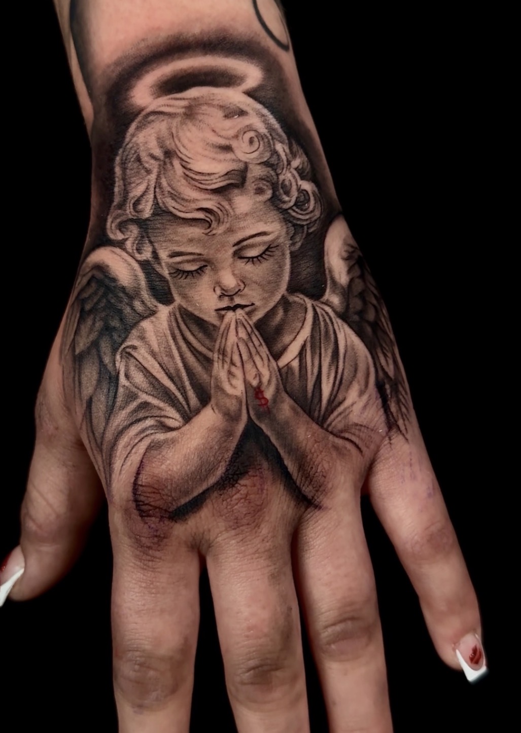 Black and grey praying cherub angel hand tattoo by Sandra